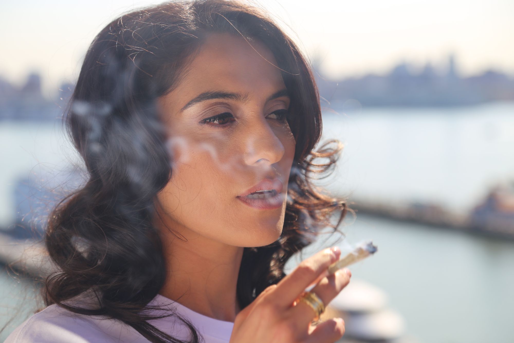 Adult woman holding a lit cannabis joint outdoors